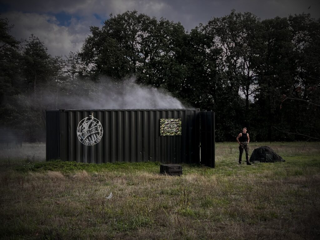 De sergeant bij de legergroene container met open deuren en rook op het veld van Red Alert in Oosterhout